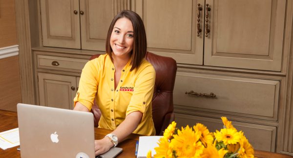 CertaPro employee sitting at desk in front of laptop in their home office.