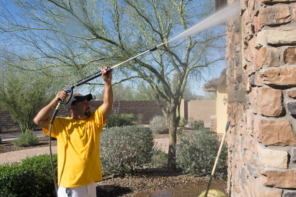 man pressure washing a house